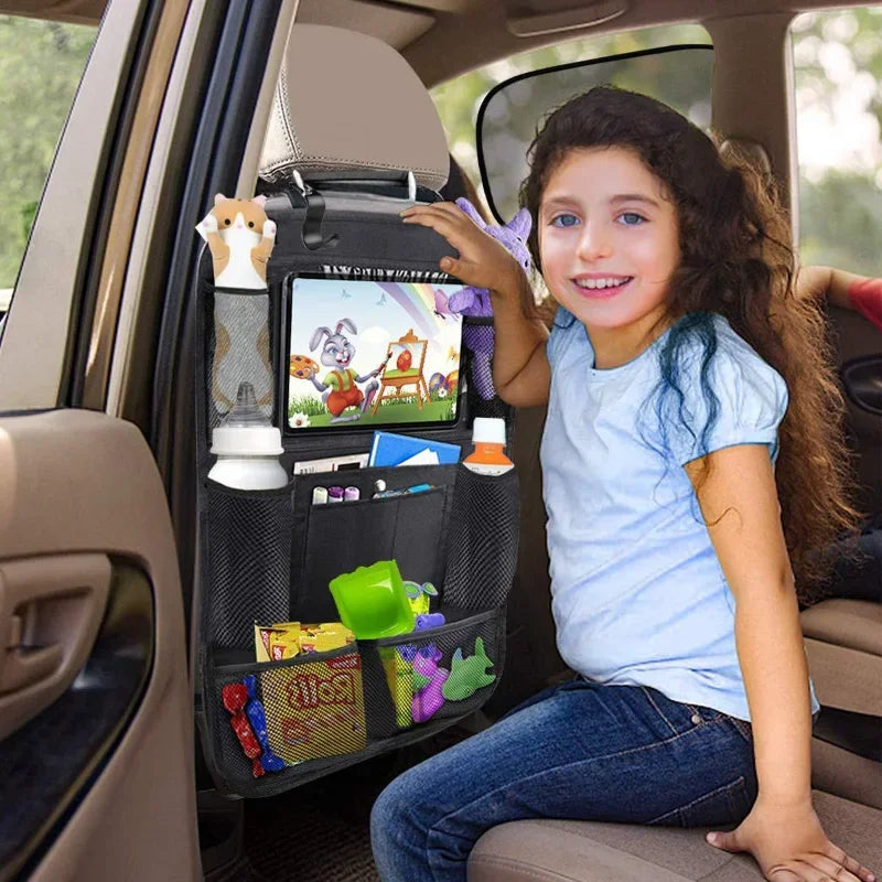 Child sitting in a car with a backseat organizer displaying toys and a tablet.