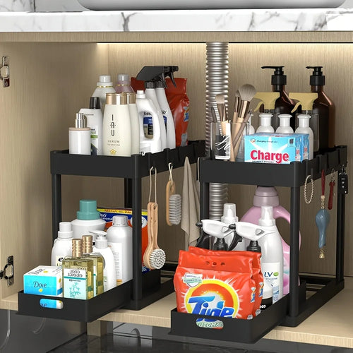 Under-sink organizer with cleaning supplies and kitchen items on a marble countertop.